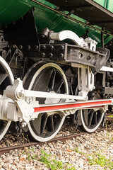 old locomotive big wheels of iron with a white rim stands on the paths close-up