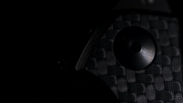 Rotation of black pocket EDC knife with carbon fiber handle. Macro view. Details of hand instrument.