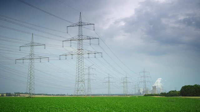 Zeitraffer von Stromtrasse mit Kraftwerk bei st&uuml;rmischem Wetter