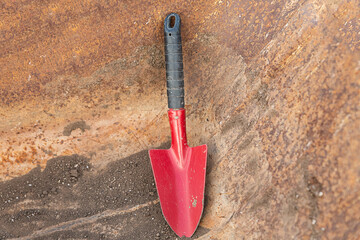 iron scoop, a small red shovel stands against a rusty and iron bucket