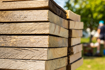 high stack of old and beige planks, side view on a blurred background of construction
