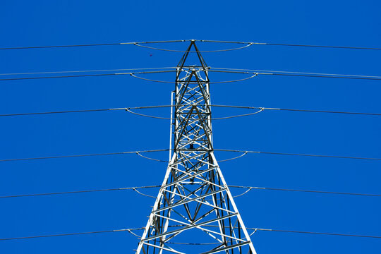 High voltage transmission tower (power tower, electricity pylon, steel lattice tower) with parallel single-circuit lines in the blue sky