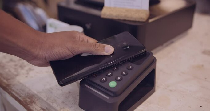 Female paying using smart phone touching card reader in shop