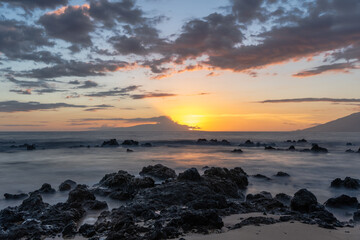 Sunset on beach in Hawaii Maui Long exposure of waves coming in.