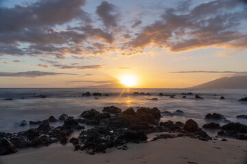 Sunset on beach in Hawaii Maui Long exposure of waves coming in with sand .