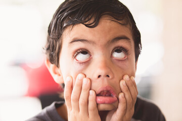 child making Funny faces  with his eyes and pulling down his face frustrated 