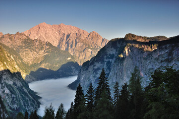 Lake Koenigssee covered with early fog in the morning, Watzmann east face already in the sun