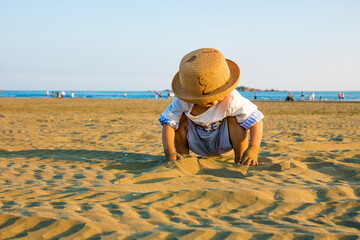 A child playing on the beach in the warm sun
