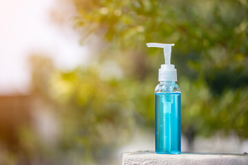 Alcohol gel outdoor in garden with blur tree and sun light in background. Alcohol gel with copy space. Hand sanitizer gel for clean and against the corona virus, covid-19, bacteria.
