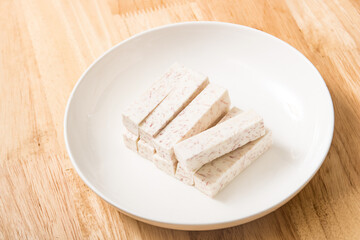 A dish of neatly cut taro pieces on a wood-grain table