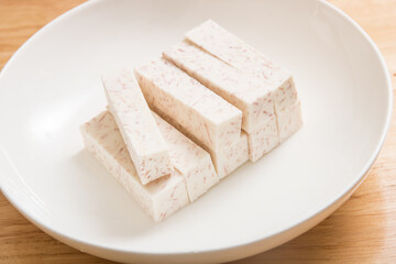 A dish of neatly cut taro pieces on a wood-grain table