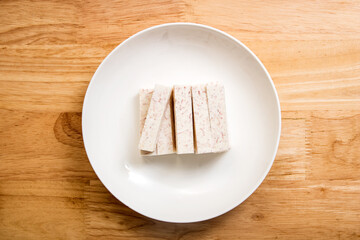 A dish of neatly cut taro pieces on a wood-grain table