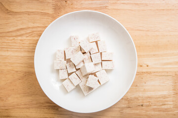 A dish of neatly cut taro pieces on a wood-grain table