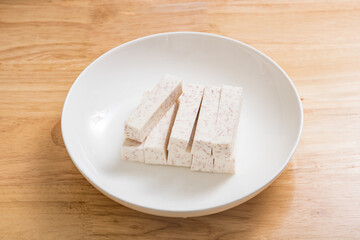 A dish of neatly cut taro pieces on a wood-grain table
