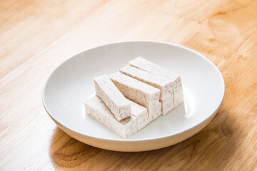 A dish of neatly cut taro pieces on a wood-grain table
