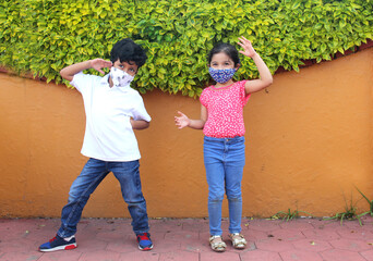 6-year-old boy and girl with protective face masks for virus covid-19, in the park, new normal