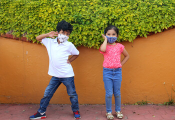 6-year-old boy and girl with protective face masks for virus covid-19, in the park, new normal