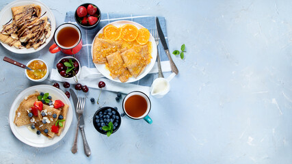 Variety of homemade crepes on grey background.