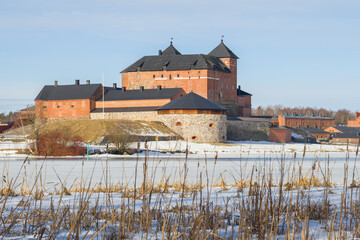 Naklejka na ściany i meble View of the ancient Hameenlinna fortress from the shore of Vanajavesi lake on a sunny March day. Finland