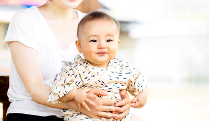 外でお母さんに抱っこされたかわいい笑顔の赤ちゃん