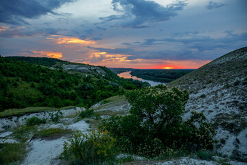 Orange sunset in cloudy weather on the Don River in the lime hills