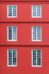 Fototapeta na wymiar Six white windows on a red facade