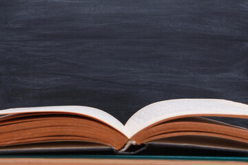 Open book against school blackboard  background. Side view, close-up, copy space, border. Learning, education, knowledge, library, love reading concept