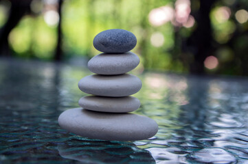 Stone cairn on green blurry background, light pebbles and stones