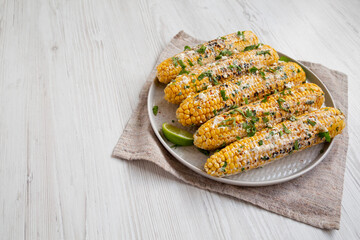 Homemade Elote Mexican Street Corn on a plate, side view. Copy space.