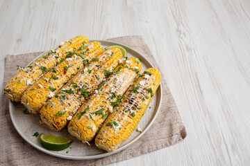 Homemade Elote Mexican Street Corn on a plate, side view. Space for text.