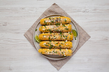 Homemade Elote Mexican Street Corn on a plate on a white wooden background, top view. Flat lay, overhead, from above.