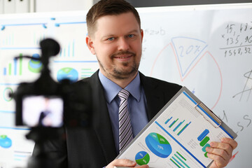 Male in suit and tie show stats graph pad making promo videoblog or photo session in office...