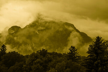 Monochrome sepia vintage style foggy mountain landscape with mist and clouds
