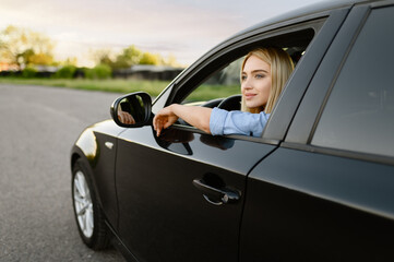 Female student poses in car, driving school