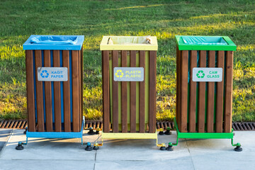 Recycling bins of different colors (yellow, green, blue) outdoors. Garbage bin in the park, trash...