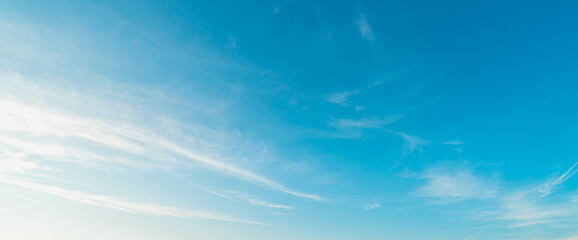 Background picture low angle of bright blue sky on a sunny day. There are fluffy white clouds and...