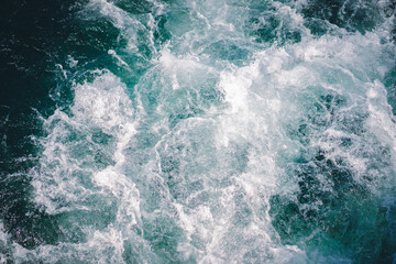 Fototapeta na wymiar The natural background of the emerald green water spreading into waves and white bubbles as the boat sails in the morning. Feeling fresh, relaxed, and cool.
