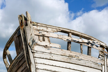 Abandoned fishing boat on the shingle beach at Dungeness with weathered and broken timbers.