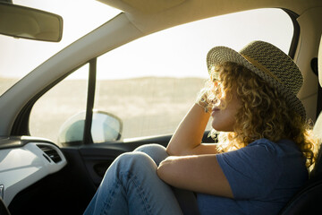 one, beautiful curly woman enjoying her vacations outdoors traveling with a car - sunset and sunny...