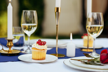 Table setting, glasses, candles, flower and sweets