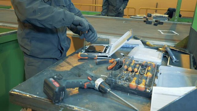 Man uses screwdriver to destroy tablet at recycling center.