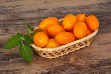 Yellow tomato heap in the wooden bowl