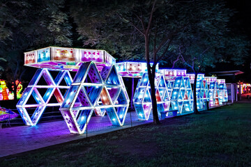 Fun in the park. A luminous tunnel with lattice walls and a roof shaped like playing cards....
