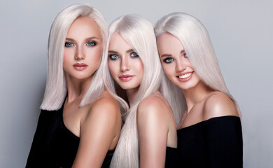 Three beautiful girls with hair coloring in blond. Straight and smooth hair coloring in ultra blond color in a beauty salon. Beauty, cosmetics and makeup
