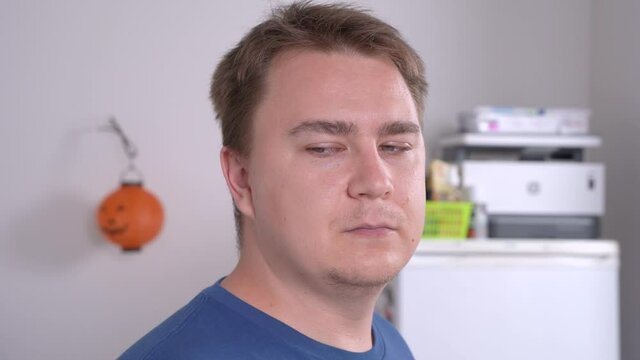 Close up portrait of young male with short hair cut points to something by eyes, brutally grining and smirking. Vivid mimics and face expression