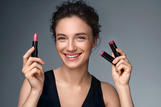 Woman applying  lipstick. Photo of woman with perfect makeup on gray background. Beauty concept