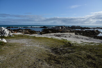 Fototapeta na wymiar Sand, rocks, sea and clouds near Agulhas, where the Indian and Atlantic Oceans meet