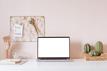 Laptop with blank white screen on office desk interior. Stylish gold workplace mockup table view. 