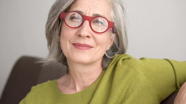 Nice senior lady in eyeglasses smiling on cam, wrinkled skin, anti-aging care