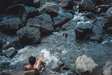 Asian boys don't wear clothes to play in the waterfalls in a beautiful natural forest.